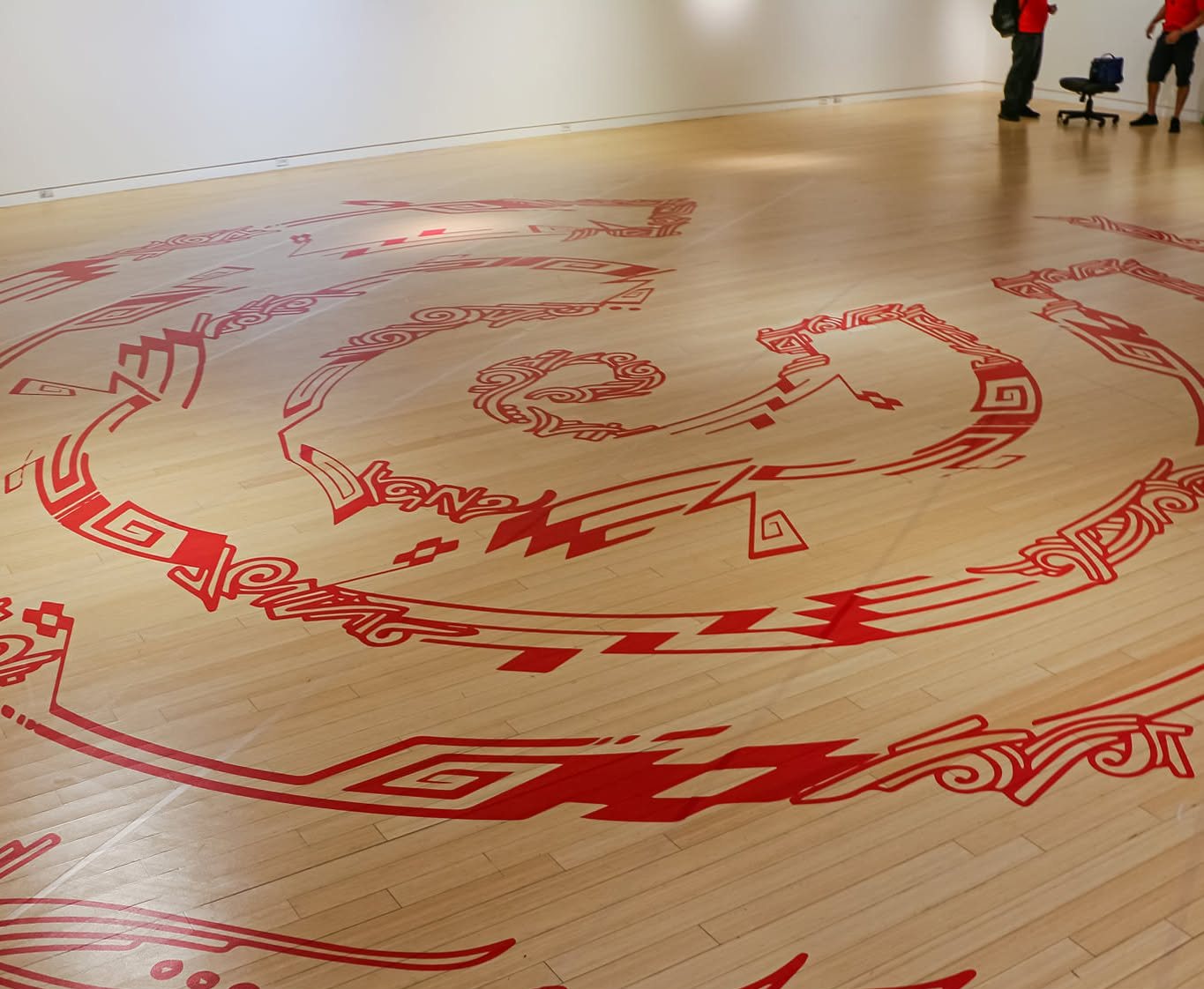 Large-format red floor graphic installed on a wood gallery floor